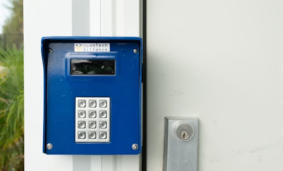 A blue keypad is mounted on a white door.