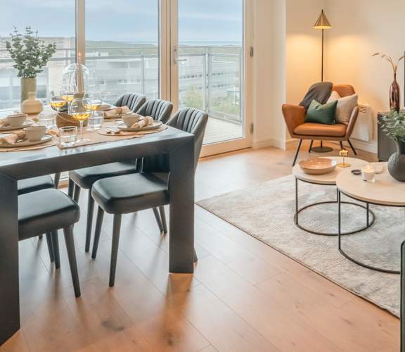 A modern living room with a dining table and a green sofa.