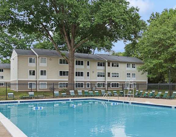 A swimming pool in front of a large apartment building.