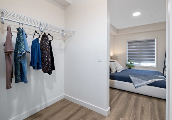 a bedroom with a bed and a closet with clothes hanging on the wall