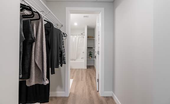 A hallway with a white door and a rack of clothes.