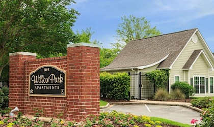 A sign for Willow Park Apartments stands in front of a building.