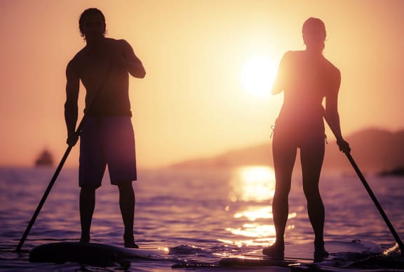 a couple of people standing on top of a paddle board