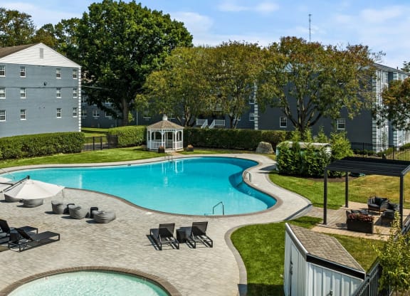 a swimming pool with lounge chairs and umbrellas in front of a building  at Chestnut Hill Village, Philadelphia, Pennsylvania