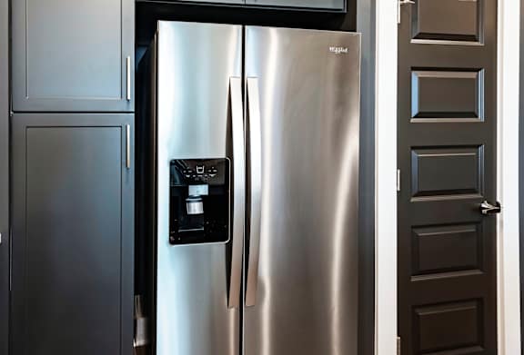 a stainless steel refrigerator in a kitchen with dark gray cabinets