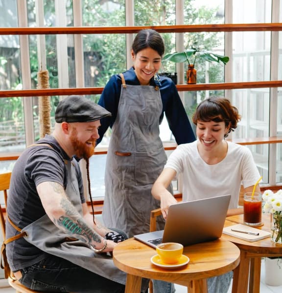 a group of people sitting around a table looking at a laptop
