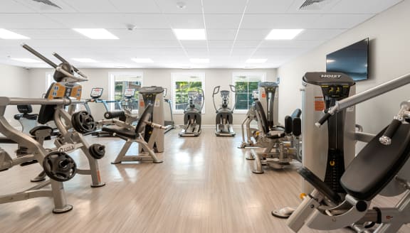 a gym with various exercise machines and a television