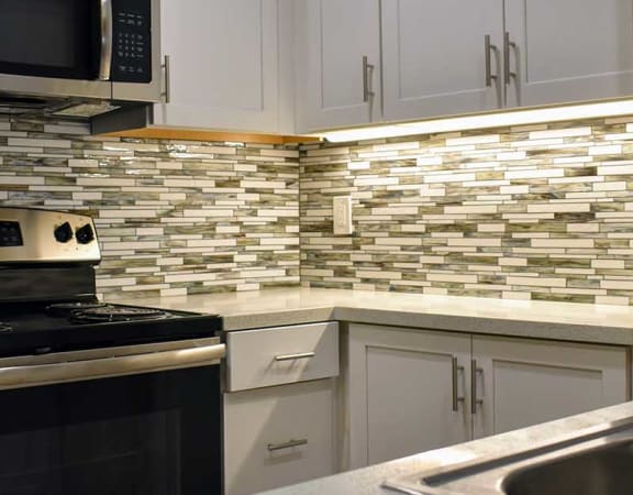 Kitchen counter with stainless sink, tiled backsplash and stainless appliances