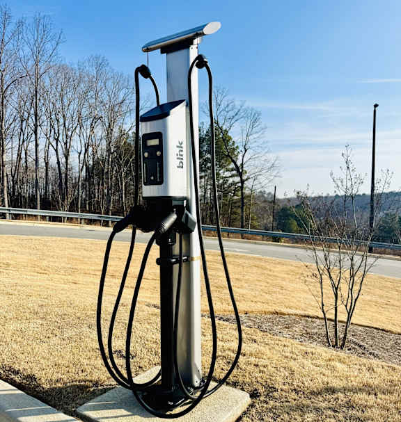 A charging station for electric vehicles is installed in a grassy area.