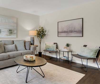 A living room with a grey couch, a coffee table, and a painting on the wall.