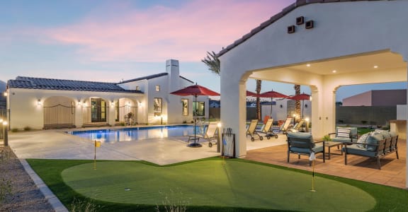 a backyard with a swimming pool and a patio with chairs and umbrellas