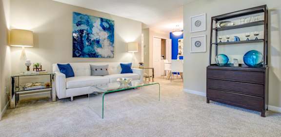 A living room with a white couch and a blue abstract painting on the wall.