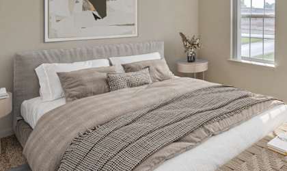 A bedroom with a large bed and a window overlooking a grassy area.