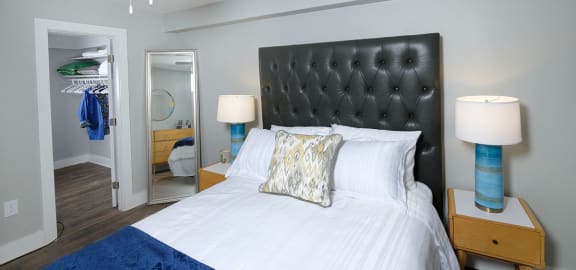 Bedroom in Mandarin Bay apartments in Jacksonville, FL with ceiling fan, walk-in closet, and large bed with leather headboard.