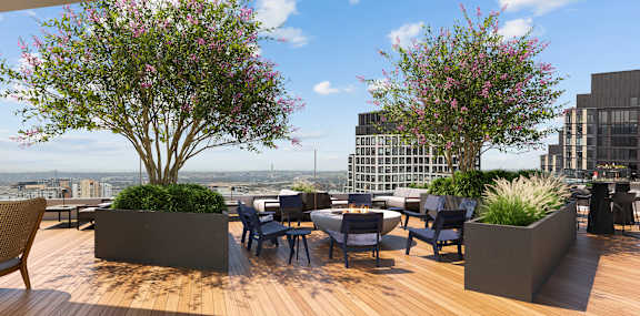 A wooden deck with a table and chairs and two flowering trees.