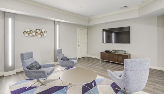 a living room with chairs and a table and a television