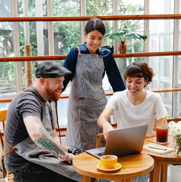 a group of people sitting around a table looking at a laptop
