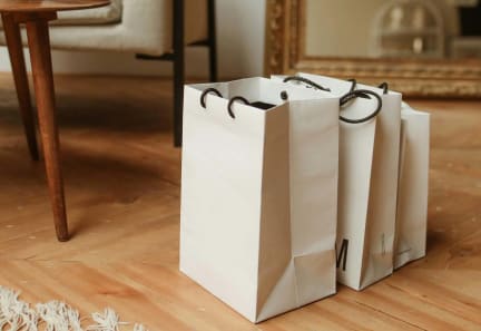 three white shopping bags sitting on the floor in front of a mirror