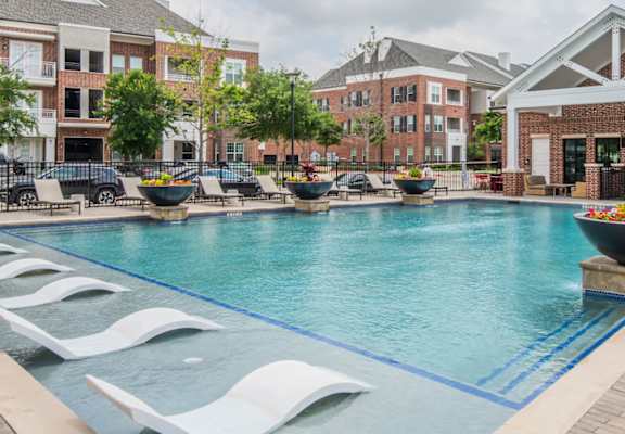 A large pool with a white bench and a building in the background.