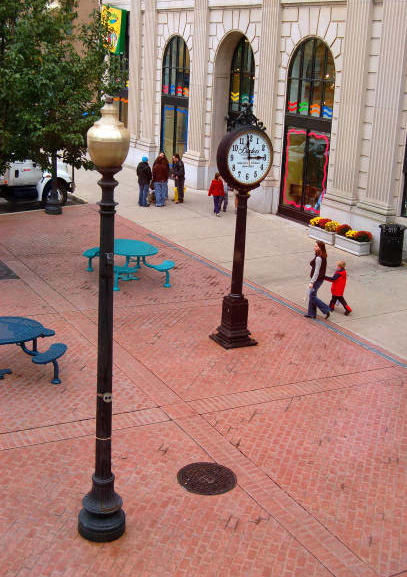 a clock on a pole on a sidewalk in front of a building