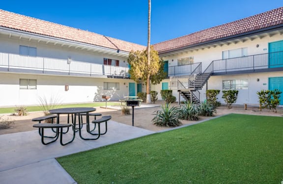 A sunny day at a courtyard with a picnic table and a green lawn.