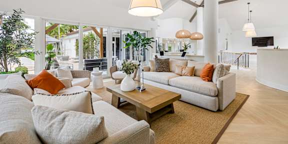 a living room with white couches and rattan chairs
