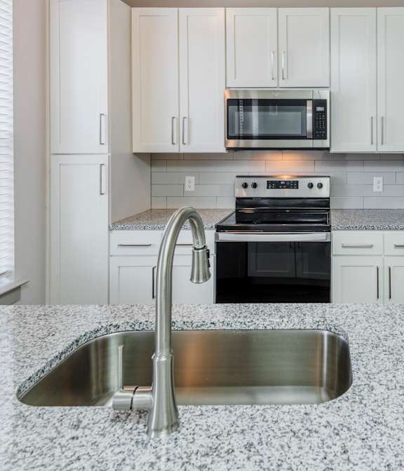 A kitchen with a granite countertop and stainless steel appliances.