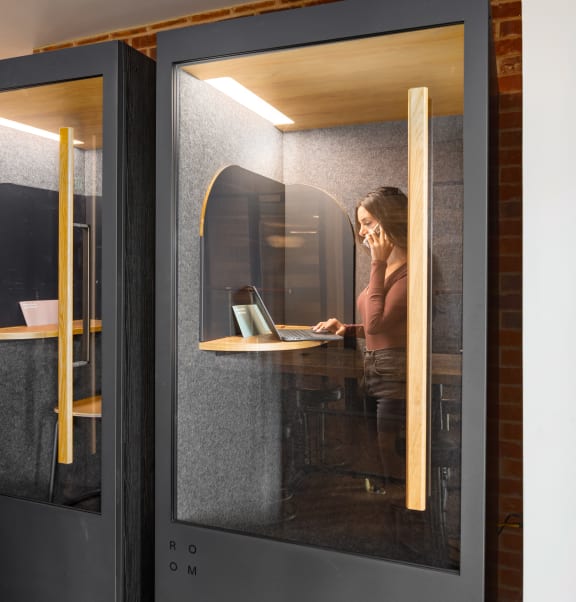a woman working on her laptop in a glass office door at Abberly Foundry Apartment Homes, Nashville