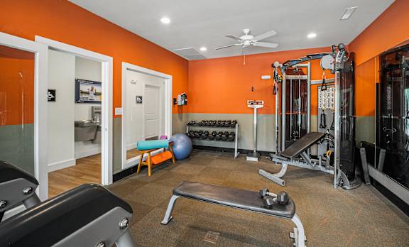 A gym with orange walls and a variety of equipment.
