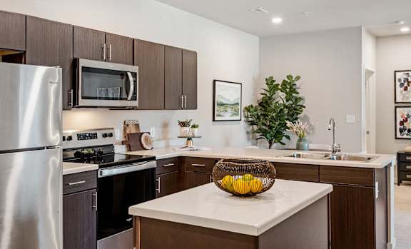 A modern kitchen with a refrigerator, stove, and microwave.