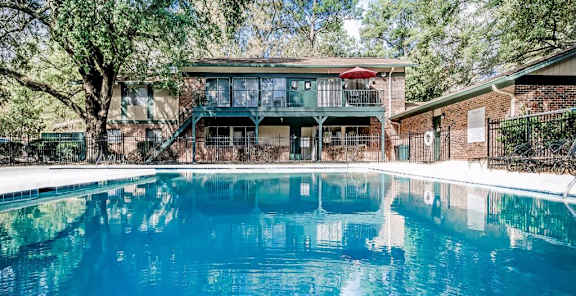 A swimming pool in front of a house with a balcony.