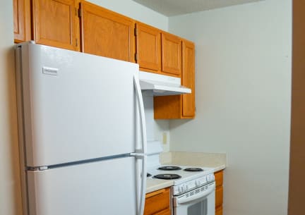 Kitchen featuring a white fridge, a white stove and hood range with wooden cabinetry.