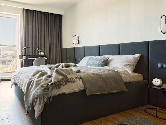 A bedroom with a large bed and a window with curtains.