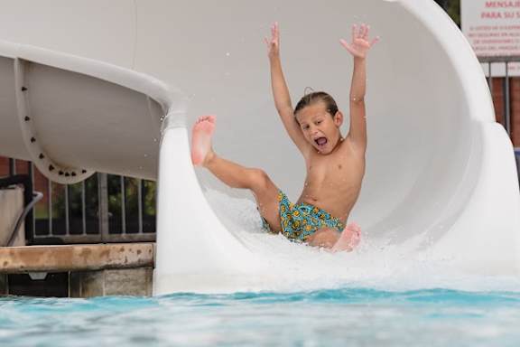 A boy sliding down a water slide at Rosemeade Apartments, California