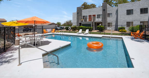 A pool with a sun lounger and umbrella.
