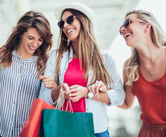 three women walking down the street with shopping bags at The Maven, Suwanee, 30024