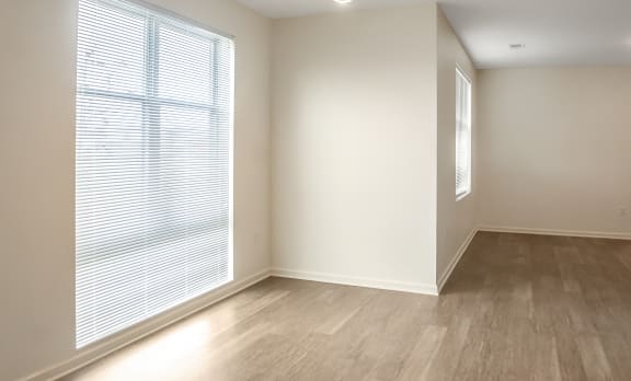 an empty living room with a large window and wood flooring