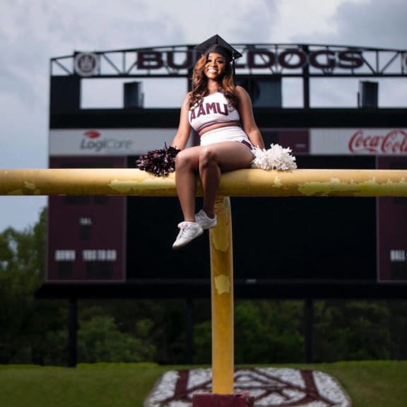 a cheerleader sits on a post at a football game