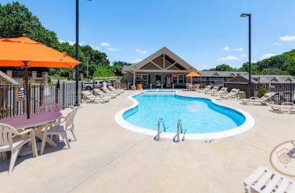 our resort style pool is surrounded by chairs and umbrellas