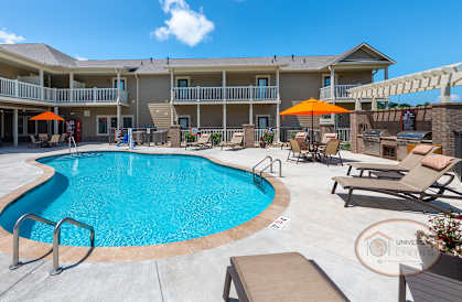 a swimming pool with chairs and umbrellas in front of a hotel