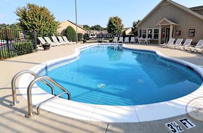 a swimming pool with chairs around it in front of a house