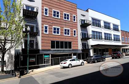 A white car is parked on the street in front of a building with a sign that says "UNIVERSAL LIVING".