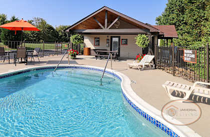 a pool house with a pool and patio with chairs and an umbrella