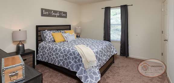 A bedroom with a bed, nightstand, and a sign on the wall that says "live laugh love".