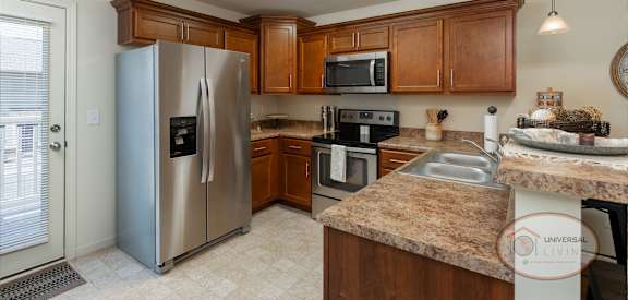 A kitchen with a refrigerator, microwave, oven, and sink.