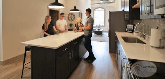 A group of people are standing around a kitchen island.