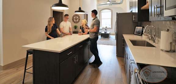 A group of people are standing around a kitchen island.