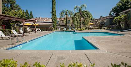River Point apartments pool and spa area with pergola, lounge chairs, tables and sun umbrellas