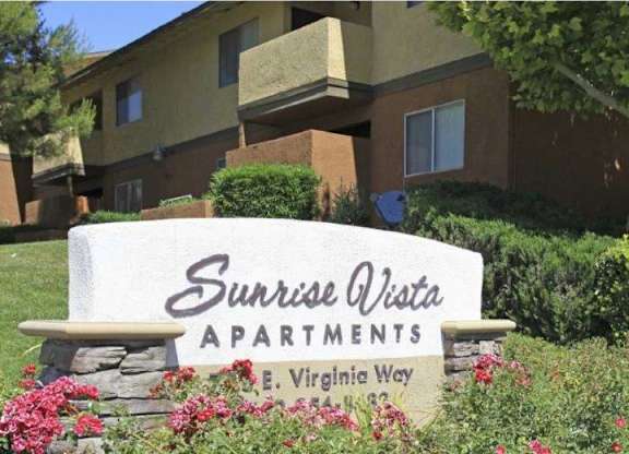 A sign for Sunrise Vista Apartments is in front of a building.