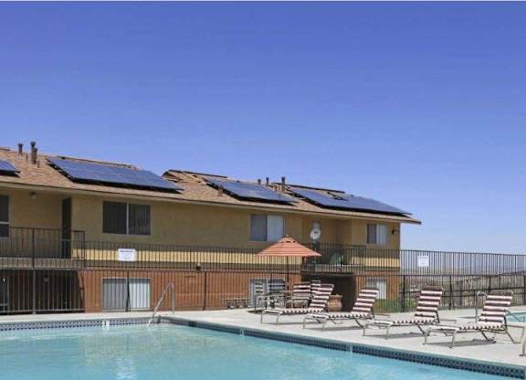 A swimming pool with lounge chairs and a building with solar panels.